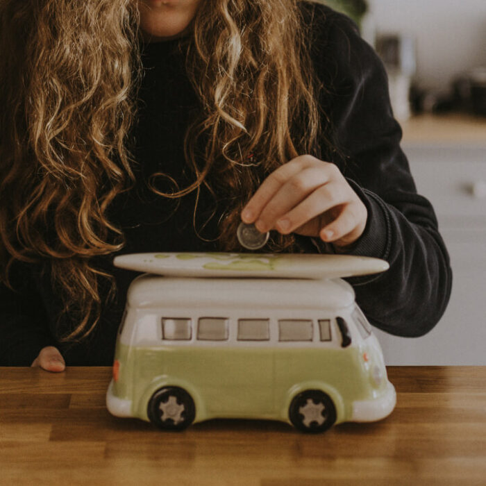 This is an image of a woman placing money in a piggybank because the cost of living is so high in the UK.